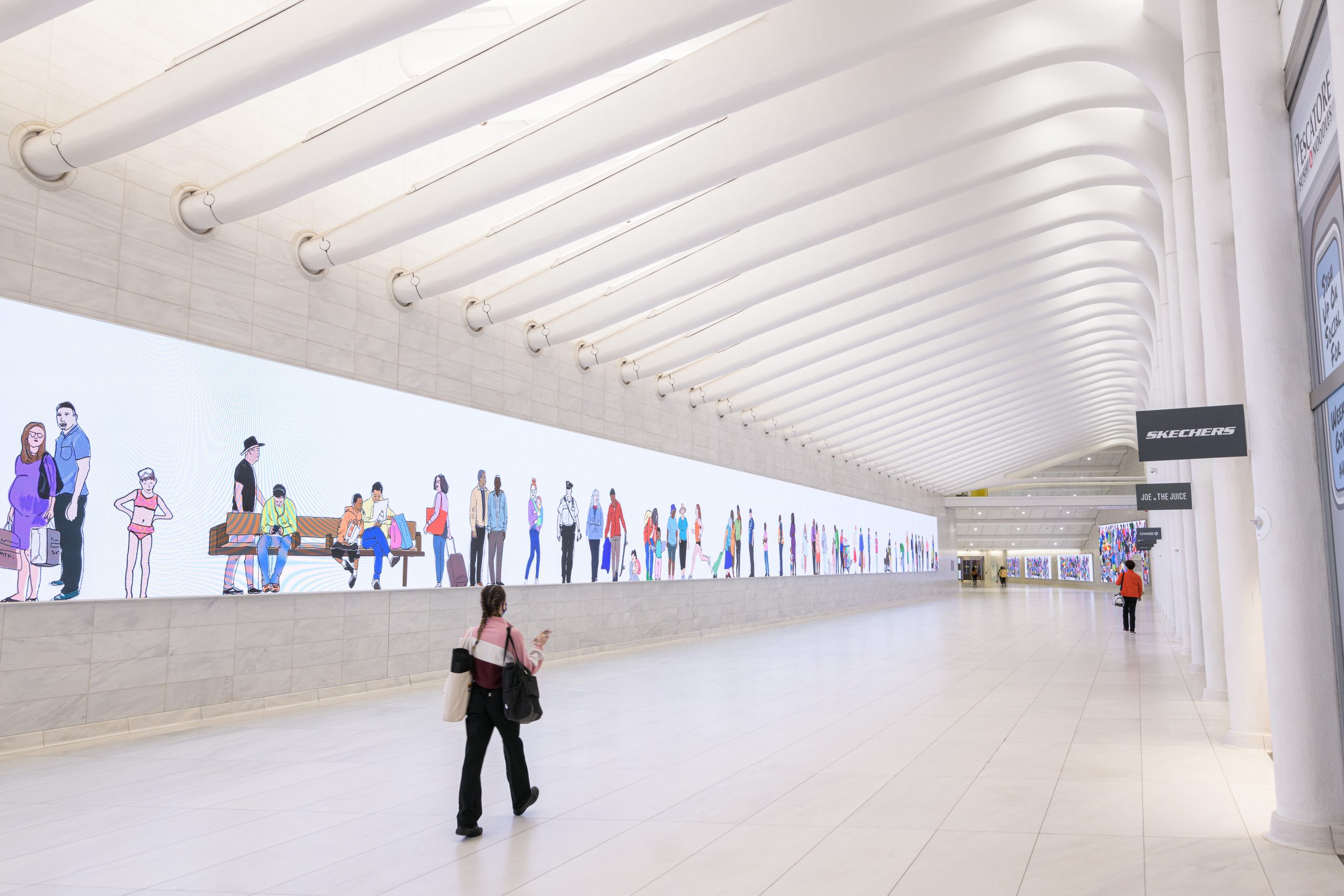 A person walks down a long, bright hallway with high ceilings in NYC's World Trade Center. To the left is a bright screen going down the length of the passageway featuring a colorful illustration created by Mona Chalabi for her project 100 New Yorkers.